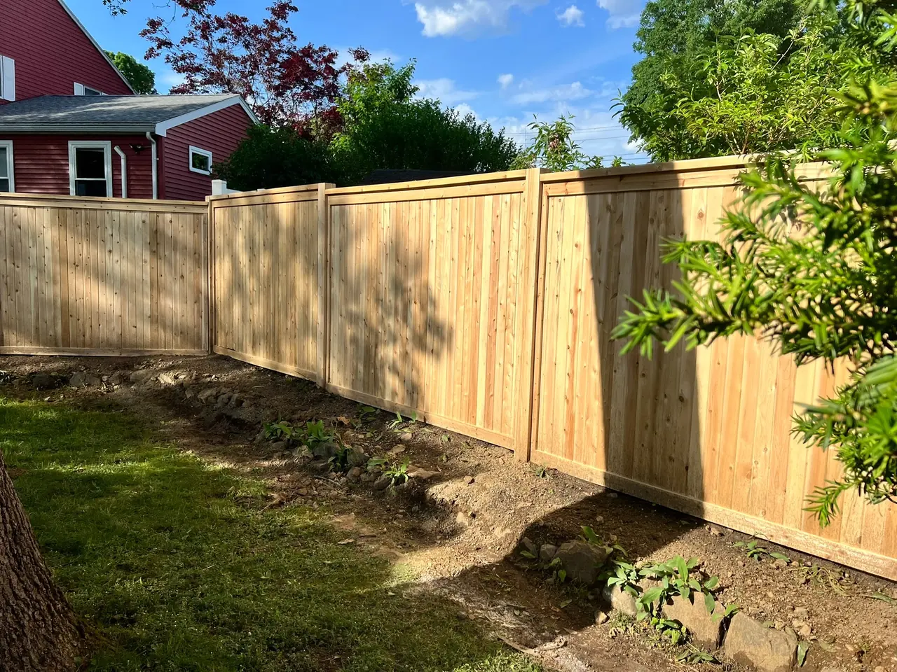 Natural cedar privacy fence installed along a backyard landscape by DM Fence Inc